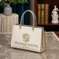 White handbag with gold logo and text on a marble surface, with a bookshelf and decorative items in the background.